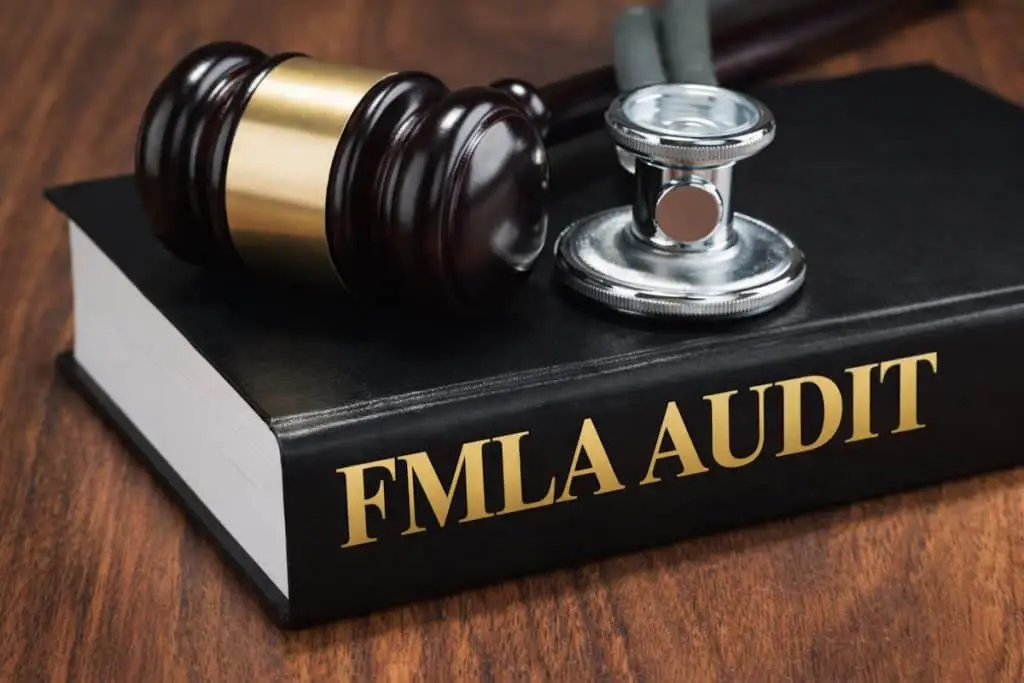 FMLA audit compliance review symbolized by legal and medical tools representing leave law risk and employer obligations